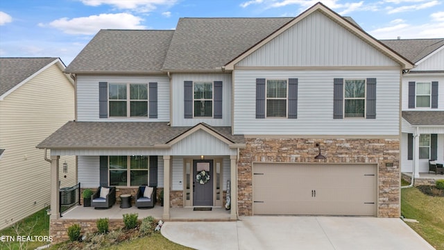 view of front of home featuring a porch, stone siding, roof with shingles, and driveway