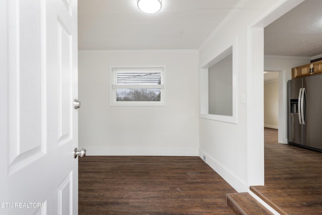 empty room with dark wood-style floors, ornamental molding, and baseboards