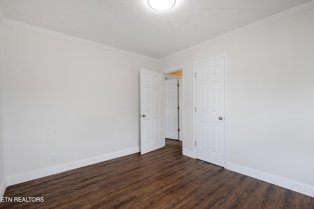 empty room featuring dark wood-type flooring, crown molding, and baseboards