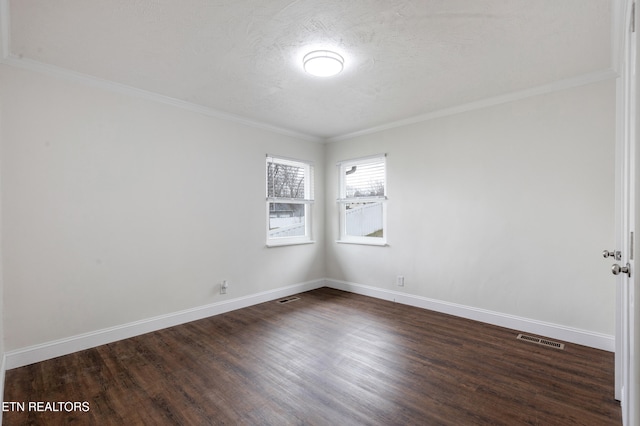 spare room with baseboards, crown molding, visible vents, and dark wood-type flooring