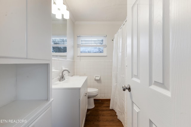 bathroom featuring toilet, wood finished floors, vanity, tile walls, and ornamental molding