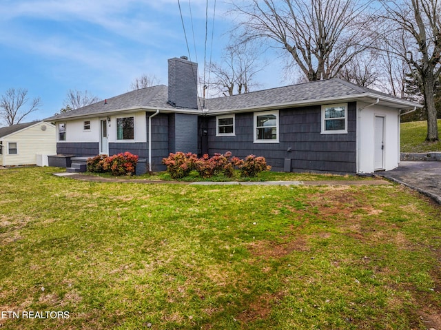 rear view of property featuring roof with shingles, a yard, and a chimney