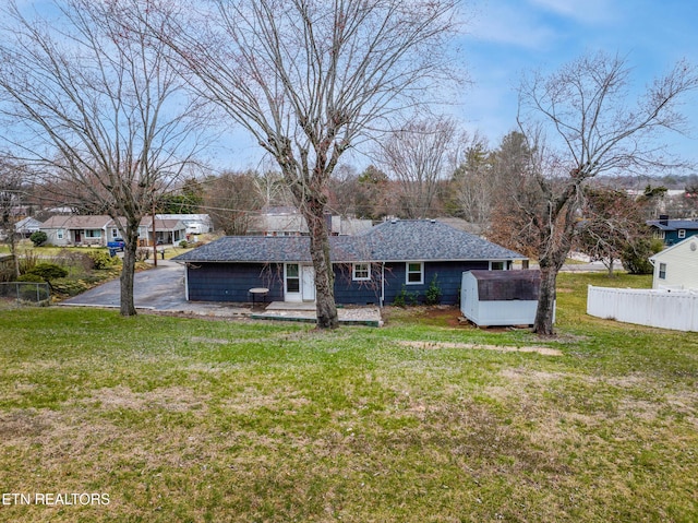 back of house with fence, a lawn, and roof with shingles