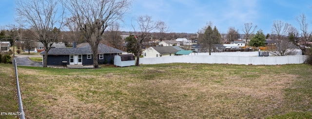 view of yard with an outbuilding, fence, and a residential view