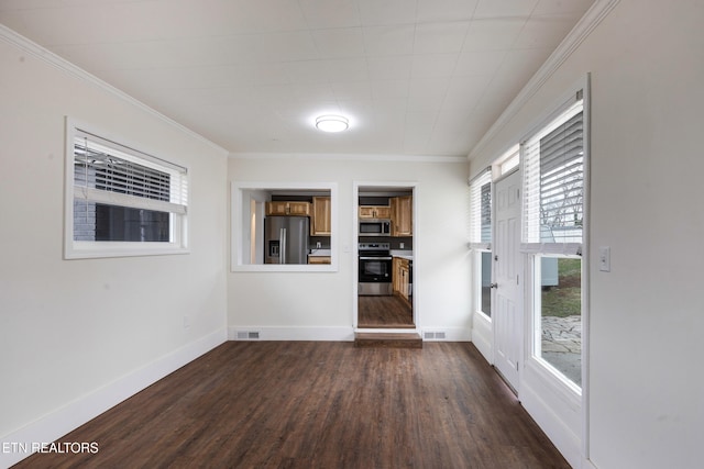 empty room featuring baseboards, dark wood-type flooring, visible vents, and crown molding