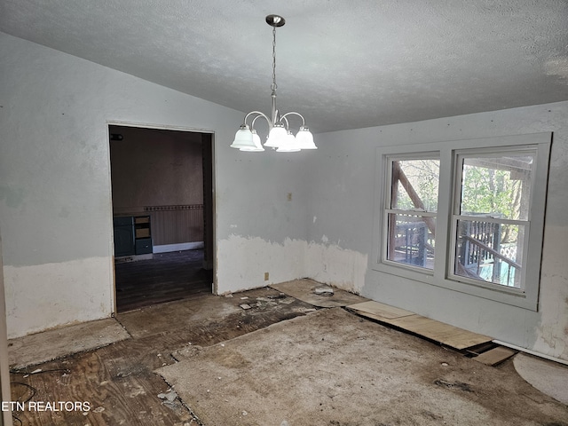 unfurnished dining area featuring vaulted ceiling, a textured ceiling, and a notable chandelier