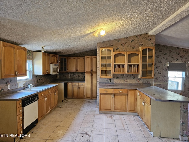 kitchen with vaulted ceiling, a sink, white appliances, a peninsula, and wallpapered walls