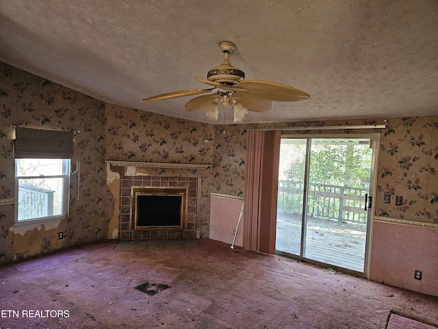 unfurnished living room featuring carpet floors, a fireplace, a textured ceiling, and wallpapered walls