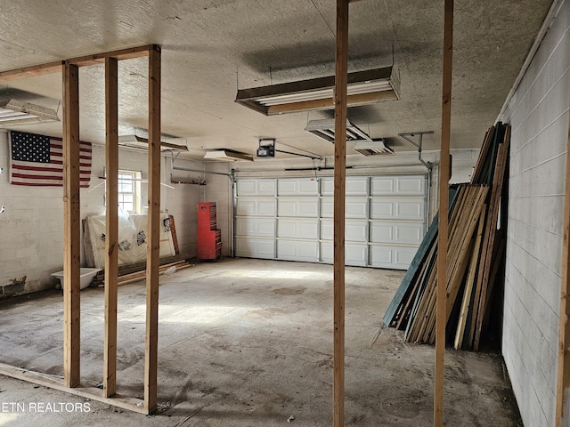 garage featuring concrete block wall and a garage door opener