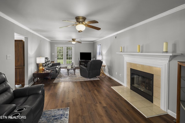 living area featuring ceiling fan, a fireplace, baseboards, wood finished floors, and ornamental molding