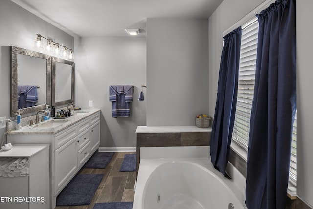bathroom with a sink, double vanity, a bath, and wood finished floors
