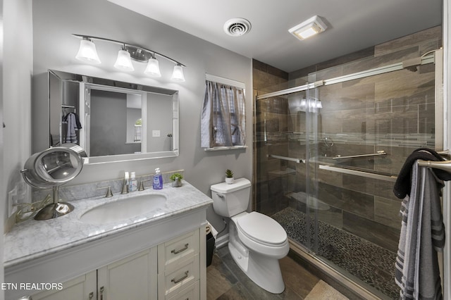 bathroom featuring vanity, a shower stall, toilet, and visible vents