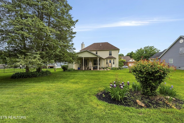 rear view of property with a lawn, fence, and a chimney
