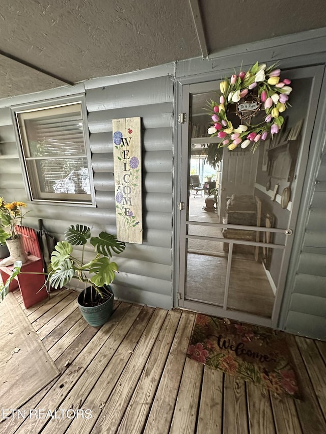 doorway to property featuring faux log siding