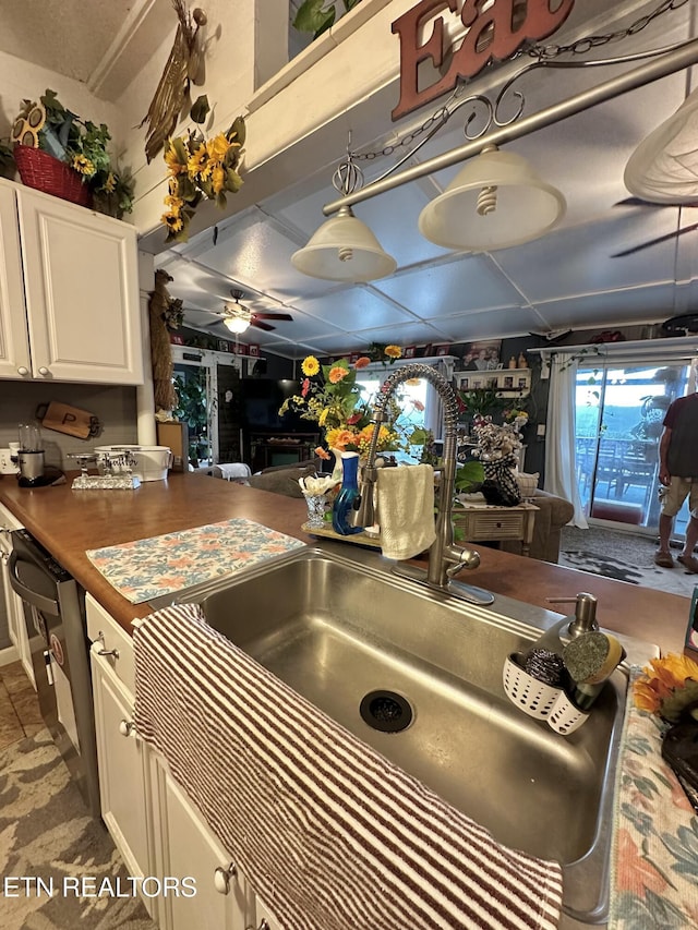 kitchen with a ceiling fan, white cabinetry, and a sink