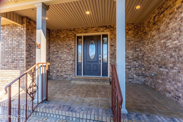 view of exterior entry with covered porch and brick siding