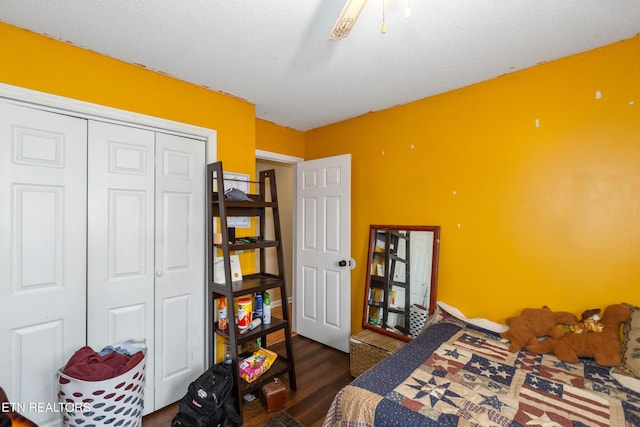 bedroom with a closet, a textured ceiling, dark wood-type flooring, and a ceiling fan