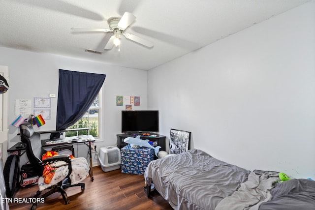 bedroom with visible vents, a textured ceiling, a ceiling fan, and wood finished floors