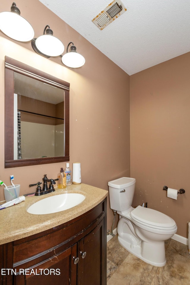 bathroom with visible vents, toilet, walk in shower, and vanity