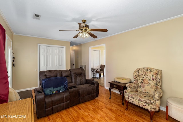 living area featuring crown molding, a ceiling fan, and light wood finished floors