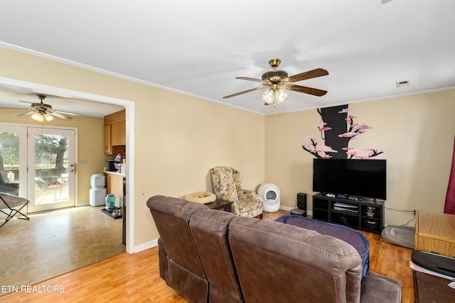 living room featuring light wood-style flooring, visible vents, ceiling fan, and ornamental molding