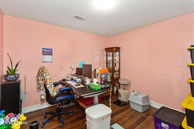 office area with visible vents, a textured ceiling, baseboards, and wood finished floors