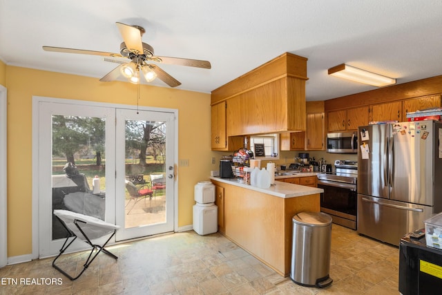 kitchen featuring ceiling fan, light countertops, brown cabinets, a peninsula, and stainless steel appliances