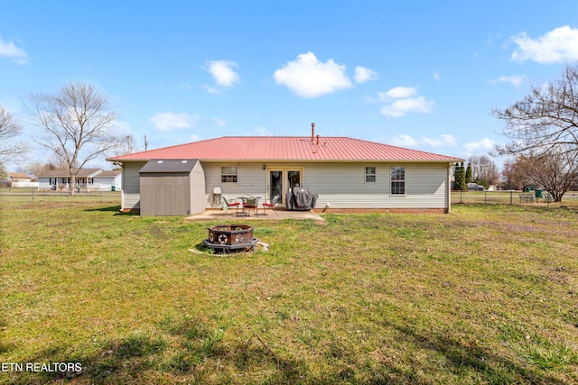 back of house featuring a storage unit, a fire pit, a yard, and fence