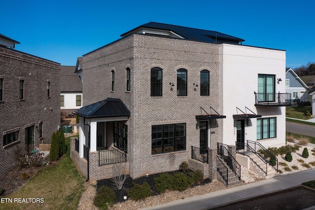 view of front of home with a standing seam roof, brick siding, and metal roof