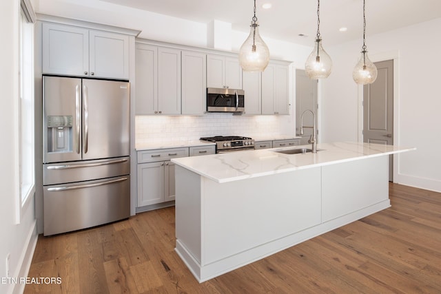 kitchen with tasteful backsplash, light stone counters, wood finished floors, stainless steel appliances, and a sink