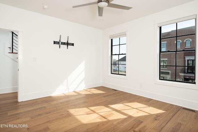 unfurnished room featuring visible vents, ceiling fan, baseboards, and wood finished floors