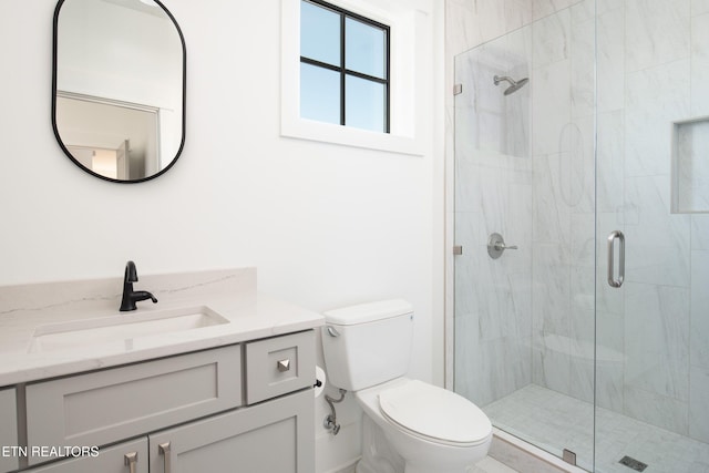 bathroom featuring toilet, a shower stall, and vanity