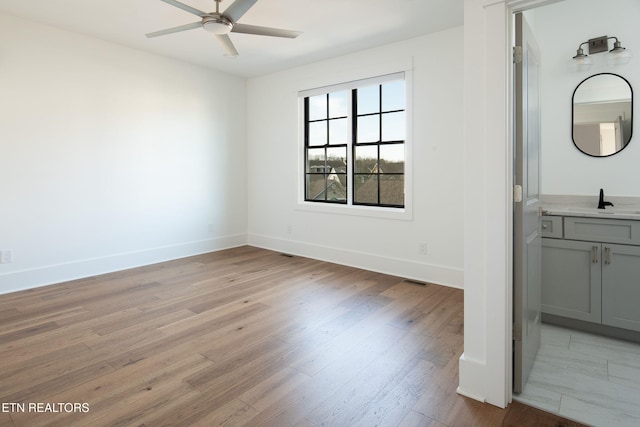 interior space featuring light wood-style floors, a sink, and baseboards