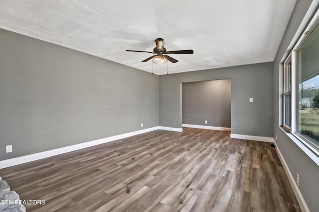 unfurnished room with a ceiling fan, baseboards, and wood finished floors