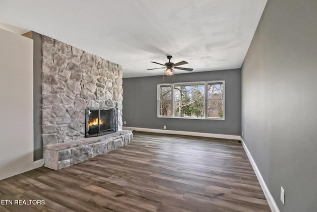 unfurnished living room featuring ceiling fan, a fireplace, baseboards, and wood finished floors