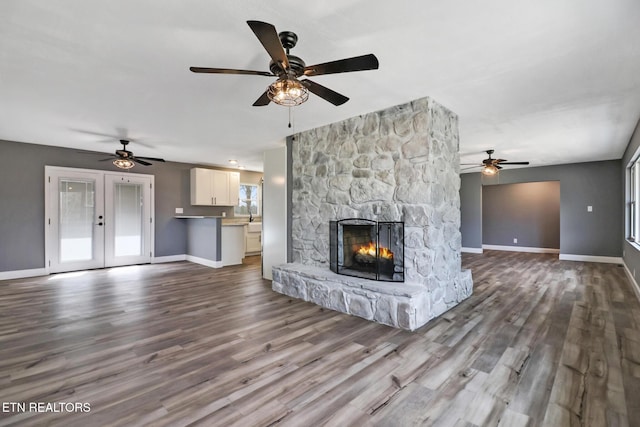 unfurnished living room with dark wood-style floors, french doors, a fireplace, and baseboards