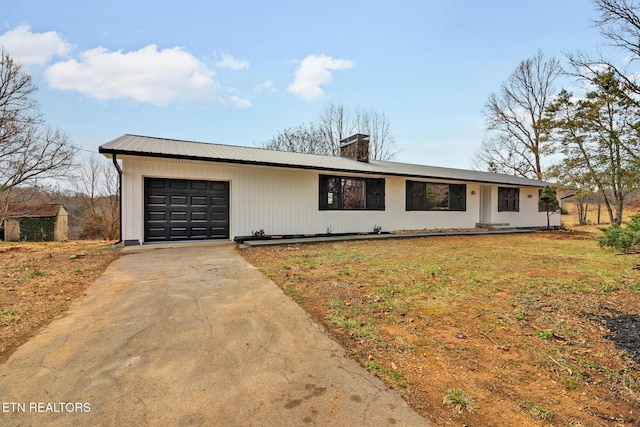 single story home with concrete driveway, a chimney, metal roof, an attached garage, and a front lawn