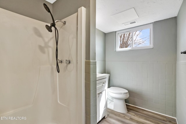 bathroom with visible vents, walk in shower, tile walls, and wood finished floors