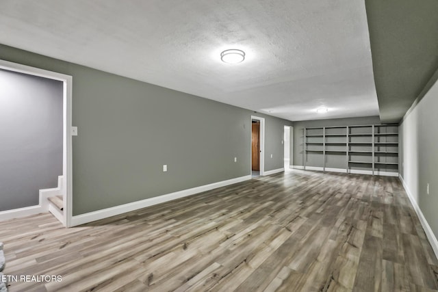 interior space with a textured ceiling, baseboards, and wood finished floors