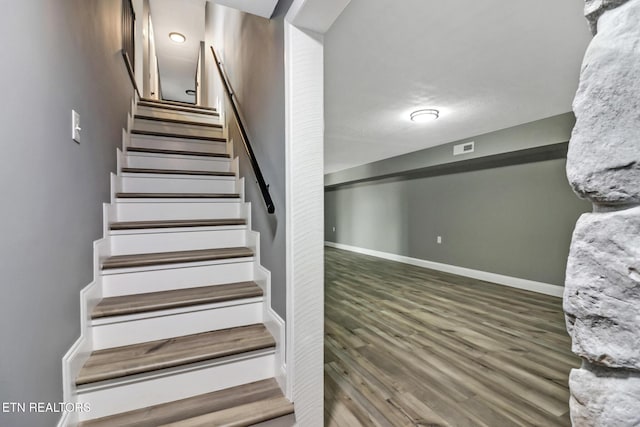 stairs with wood finished floors, visible vents, and baseboards