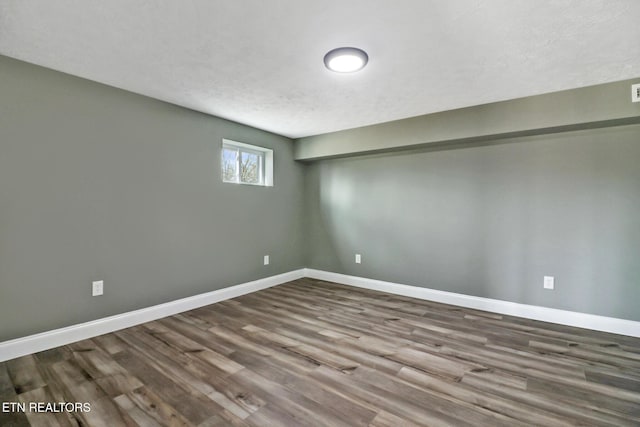 below grade area featuring a textured ceiling, wood finished floors, and baseboards