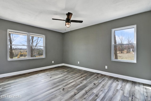 unfurnished room featuring wood finished floors, a ceiling fan, and baseboards