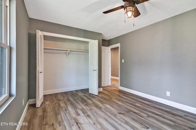 unfurnished bedroom with a ceiling fan, a closet, baseboards, and wood finished floors