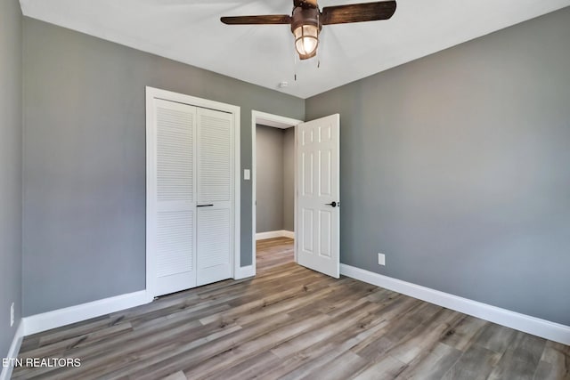 unfurnished bedroom with a ceiling fan, a closet, baseboards, and wood finished floors