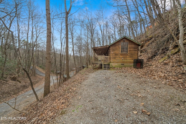 view of home's exterior with driveway, crawl space, and cooling unit