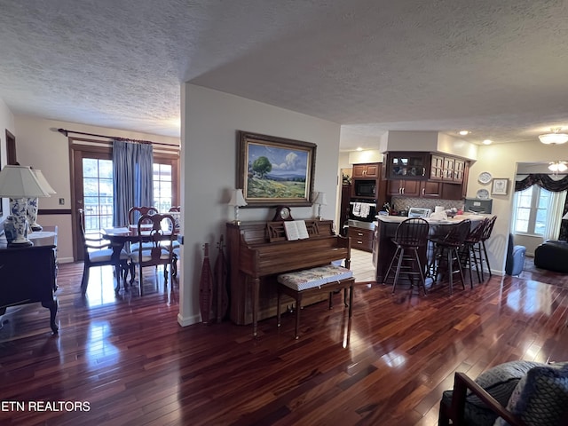 living room featuring a textured ceiling, baseboards, and dark wood-style flooring