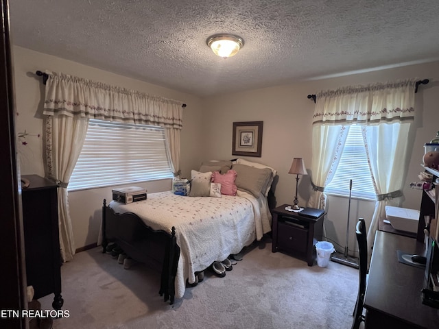 bedroom with light colored carpet and a textured ceiling