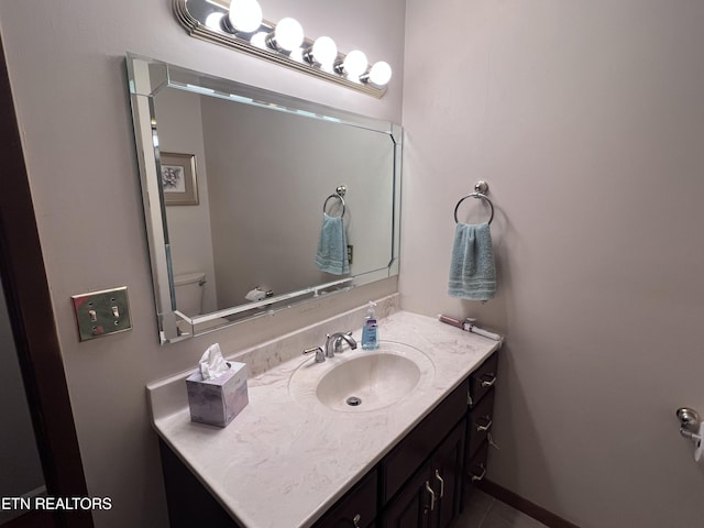 half bath featuring toilet, vanity, and baseboards