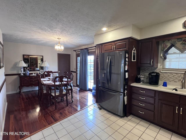 kitchen featuring plenty of natural light, light countertops, backsplash, and black fridge with ice dispenser