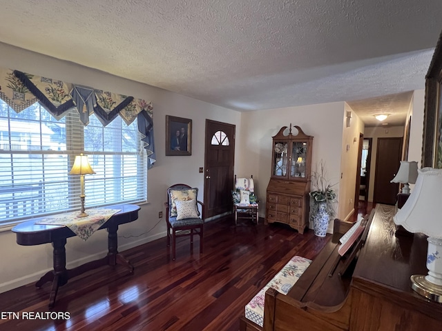 living room featuring a textured ceiling, wood finished floors, and baseboards